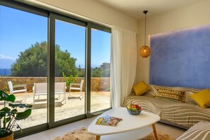 Un salon moderne avec un canapé, une table basse et un magazine. Une grande fenêtre offre une vue sur l’extérieur.