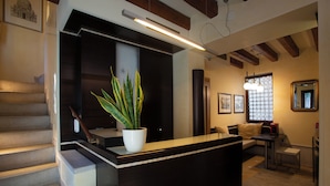 Un interior moderno con un mostrador de recepción, escalera, zona de estar y un amplio ventanal con un diseño geométrico.