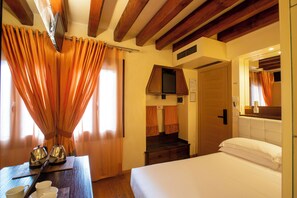 A hotel room with a wooden ceiling, a bed with white linens, a wooden nightstand with a kettle and cups, and a window with orange curtains. - Ca' dei Dogi (Venice)