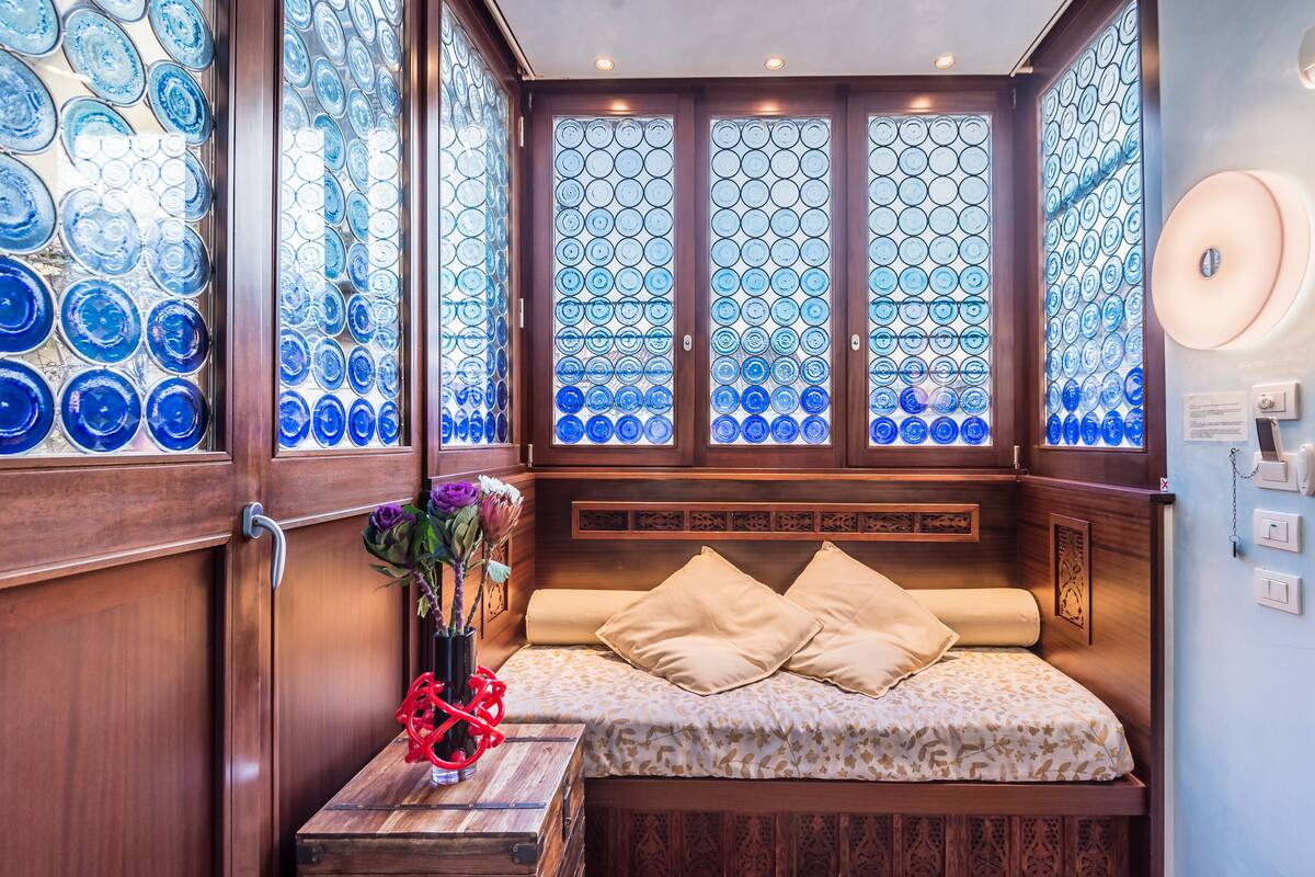 A cozy room with a bed, a wooden side table, and a vase with flowers.