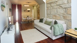 A living room with a white sofa, a wooden coffee table, and a stone accent wall. - Oporto Yellow Villas 7 (Porto)