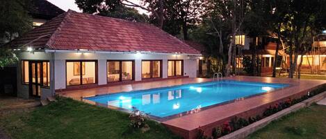 Une maison moderne dotée d’une piscine, de grandes fenêtres et d’un toit rouge.