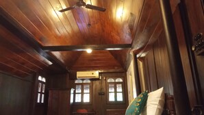 A wooden room with a bed, a ceiling fan, and a window. - Shantitheeram Ayurveda (Cherthala)