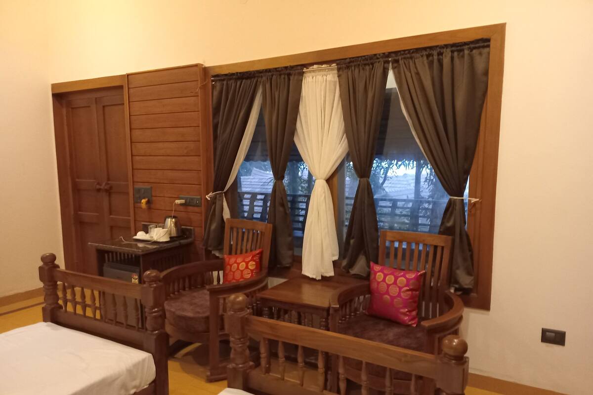 A cozy room with two wooden beds, a small table with a kettle, and a window with curtains.
