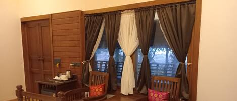 A cozy room with two wooden beds, a small table with a kettle, and a window with curtains.