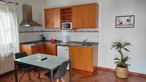 Una cucina compatta con mobili in legno, un forno a microonde, un lavandino e un tavolo con sedie.