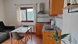 Un ambiente compatto con angolo ristoro, angolo cottura e una finestra con tende.