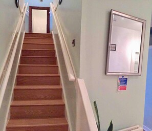 Un escalier avec des marches en bois et des rampes blanches, menant à une porte située en haut.