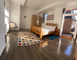 A bedroom with a wooden bed, a polka dot rug, a chair, and a wardrobe.