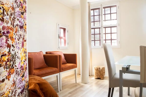Relax in this stylish living area with a sofa, dining table, and large window offering a view.