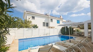 A swimming pool with lounge chairs and a white fence. - Protaras Serifos Villa Sv07 (Paralimni)