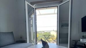 A modern room with a white table, a grey sofa, and a glass door leading to an outdoor area with a table and chairs. - Villa Rodelia in Roda 2bedroom nr3 (Roda)
