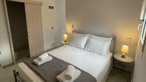 A hotel room with a bed, bedside tables, a lamp, an air conditioning unit, and a door. - Villa Rodelia in Roda 2bedroom nr3 (Roda)