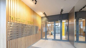Una entrada de edificio moderna con un revestimiento de paneles de madera y un área de taquillas de metal.