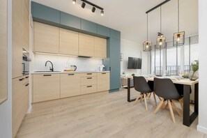 Una cocina moderna con armarios de madera clara, una isla central e iluminación colgante.