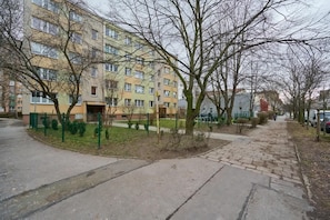 Un edificio residencial de varios pisos con un sendero pavimentado y árboles.
