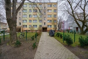 Un edificio residencial de varios pisos con un camino de ladrillo que lleva a la entrada.