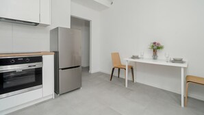 A modern kitchen with stainless steel appliances, a dining area with a white table and chairs, and a small potted plant on the table. - Stylish Studio near the Fair | Private Parking (Poznan)