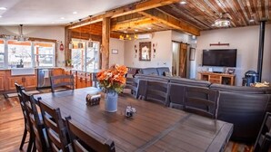 Amplia sala de estar con mesa de comedor de madera, asientos cómodos, televisor y chimenea.