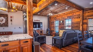 Un interior rústico con paredes de madera, encimera de piedra, chimenea y zona de estar.