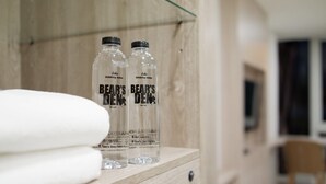 Two bottles of Bear's Den drinking water on a wooden shelf in a hotel room. - Bears Den Pattaya (Pattaya)