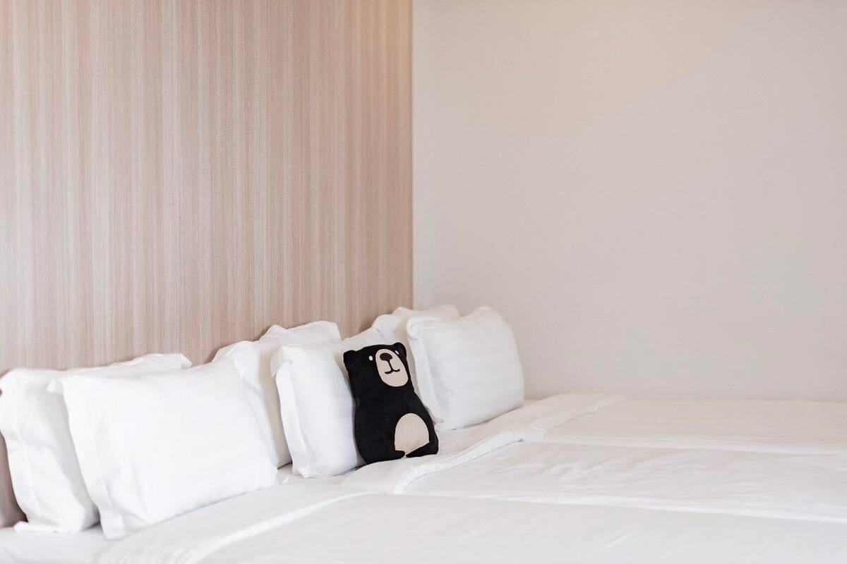 A neatly made bed with white bedding and a black and white pillow.