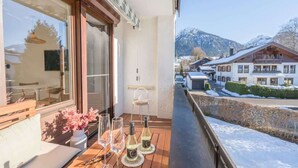 Een balkon met een houten tafel, twee flessen wijn en glazen.