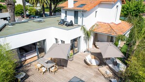 Et moderne hus med tagterrasse, udendørs møbler og swimmingpool.