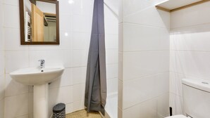 A small bathroom with a white sink, a mirror, a shower curtain, and a toilet.