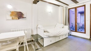 A modern bedroom with a white bed, a glass table, and a white radiator.
