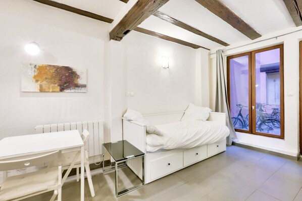 Une chambre à coucher moderne avec un lit blanc, une table en verre et un radiateur blanc.
