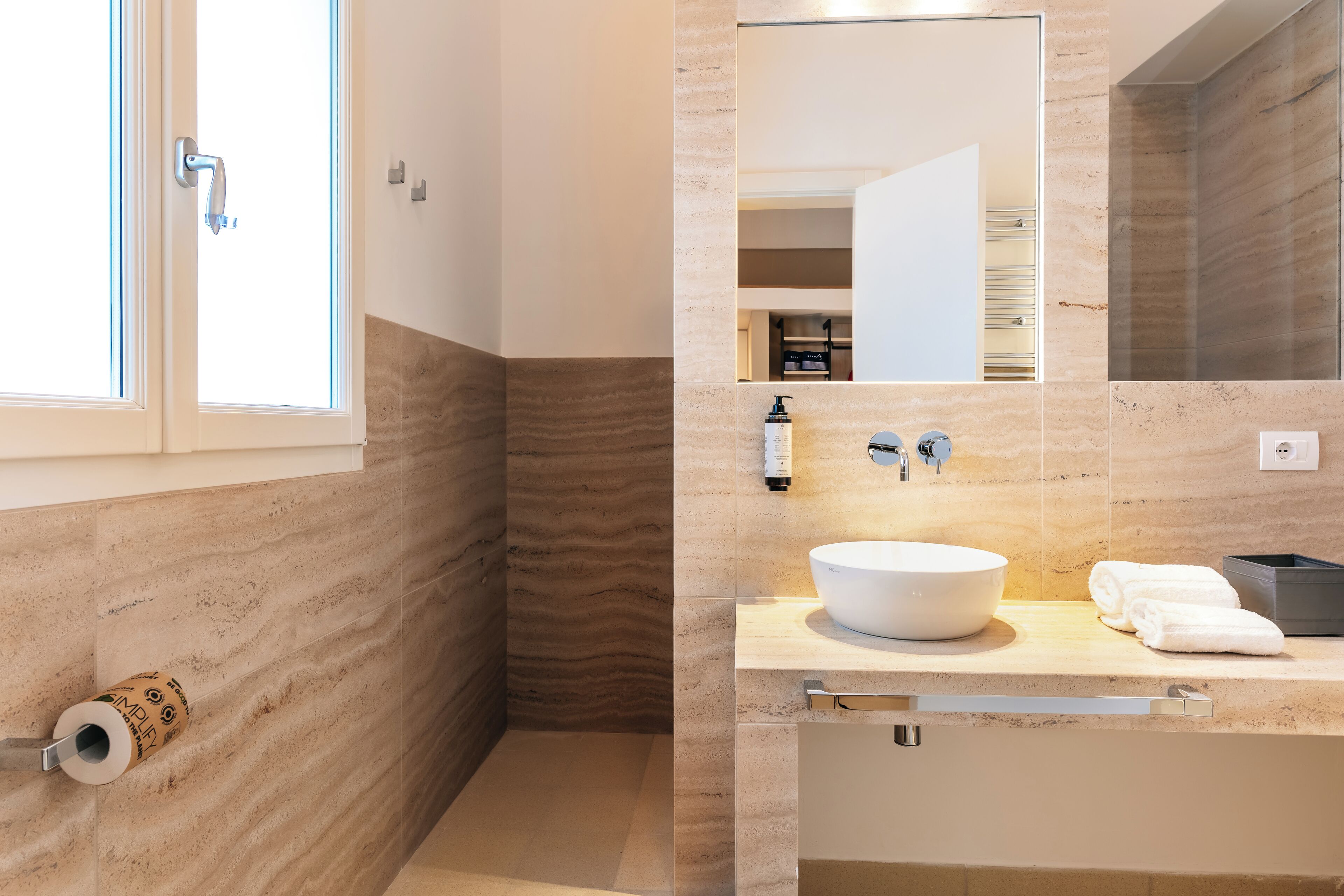 A modern bathroom with a large mirror, a round sink, and a toilet.