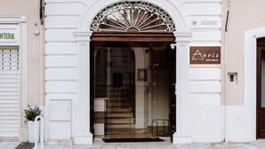 A building entrance with a glass door, a white archway, and a sign for 'Aeris Suites & Relax'. - Aeris Suite & Relax (Polignano a Mare)