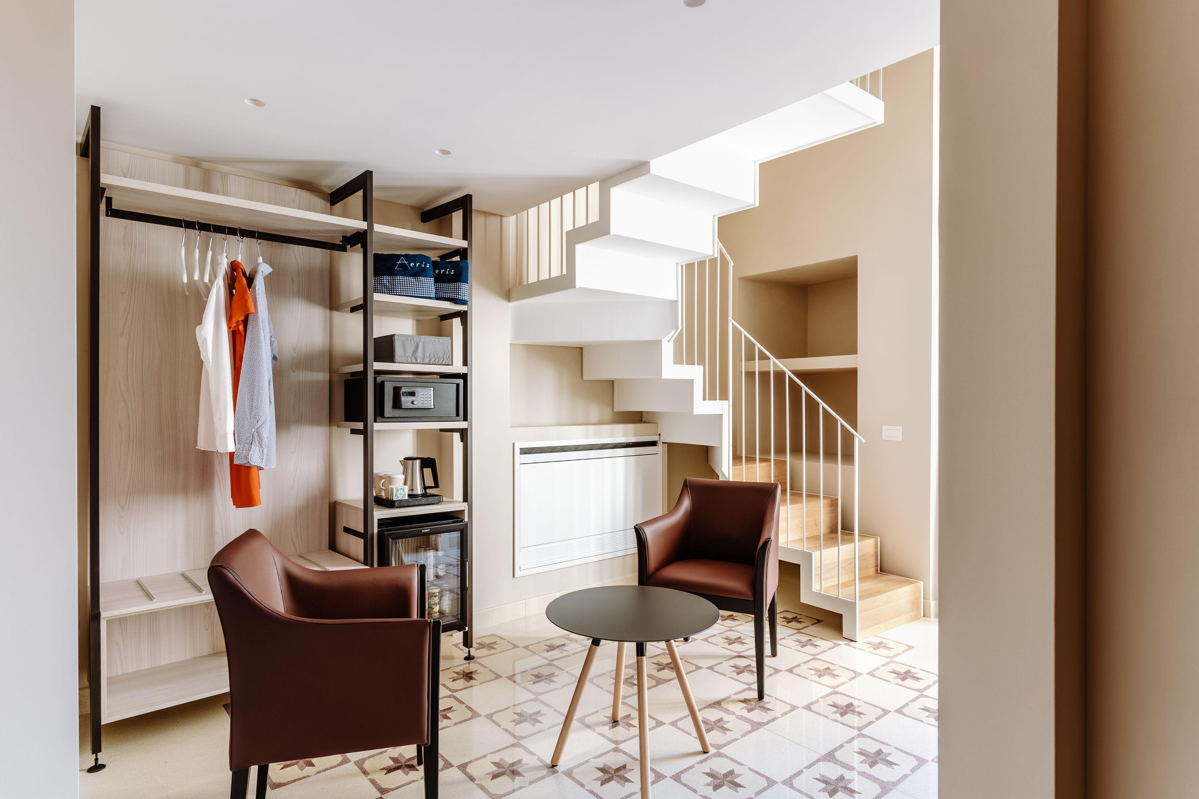 Una sala moderna con un sofá, sillas, una mesa de centro, una estantería y una escalera.