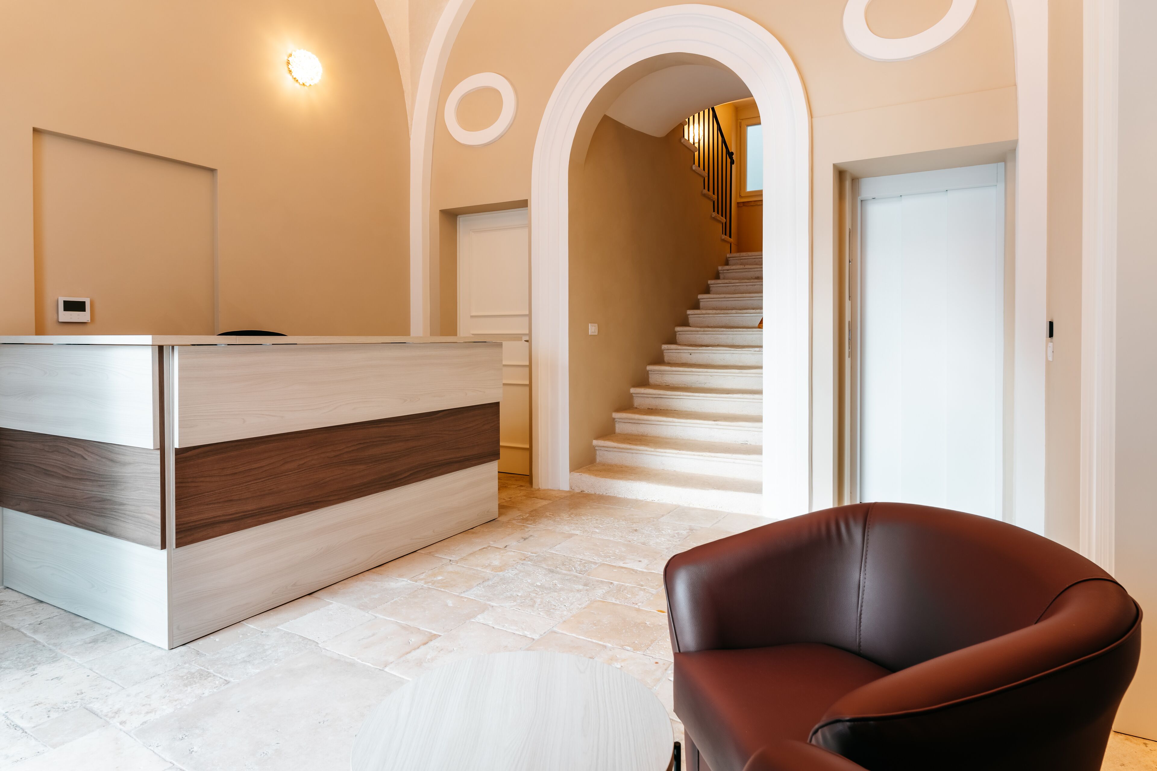 A reception area with a modern desk, a staircase, and a leather chair.