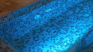 Piscina com borda azulejada e luz azul.