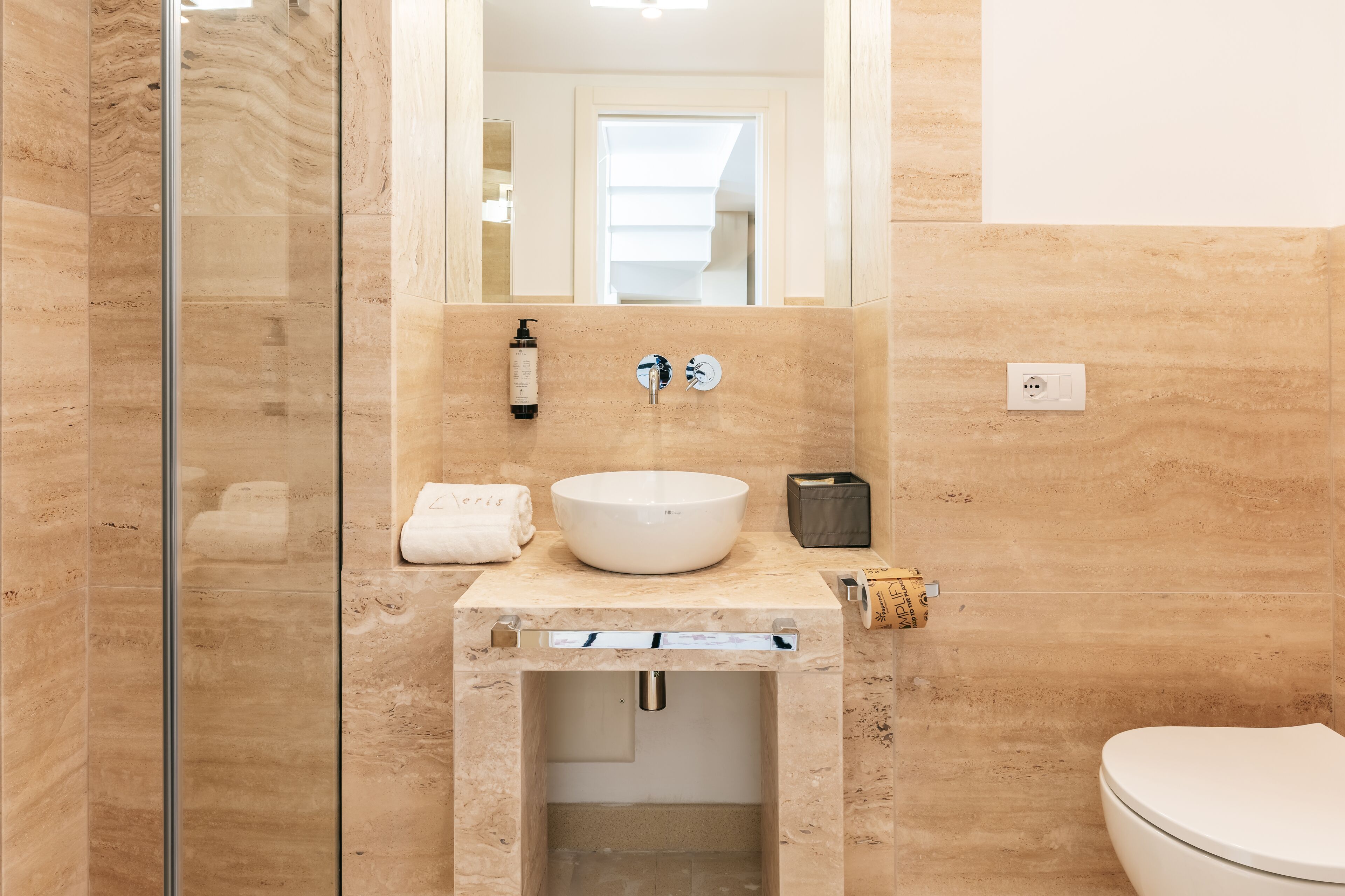 A bathroom with a marble sink, a toilet, and a glass shower enclosure.