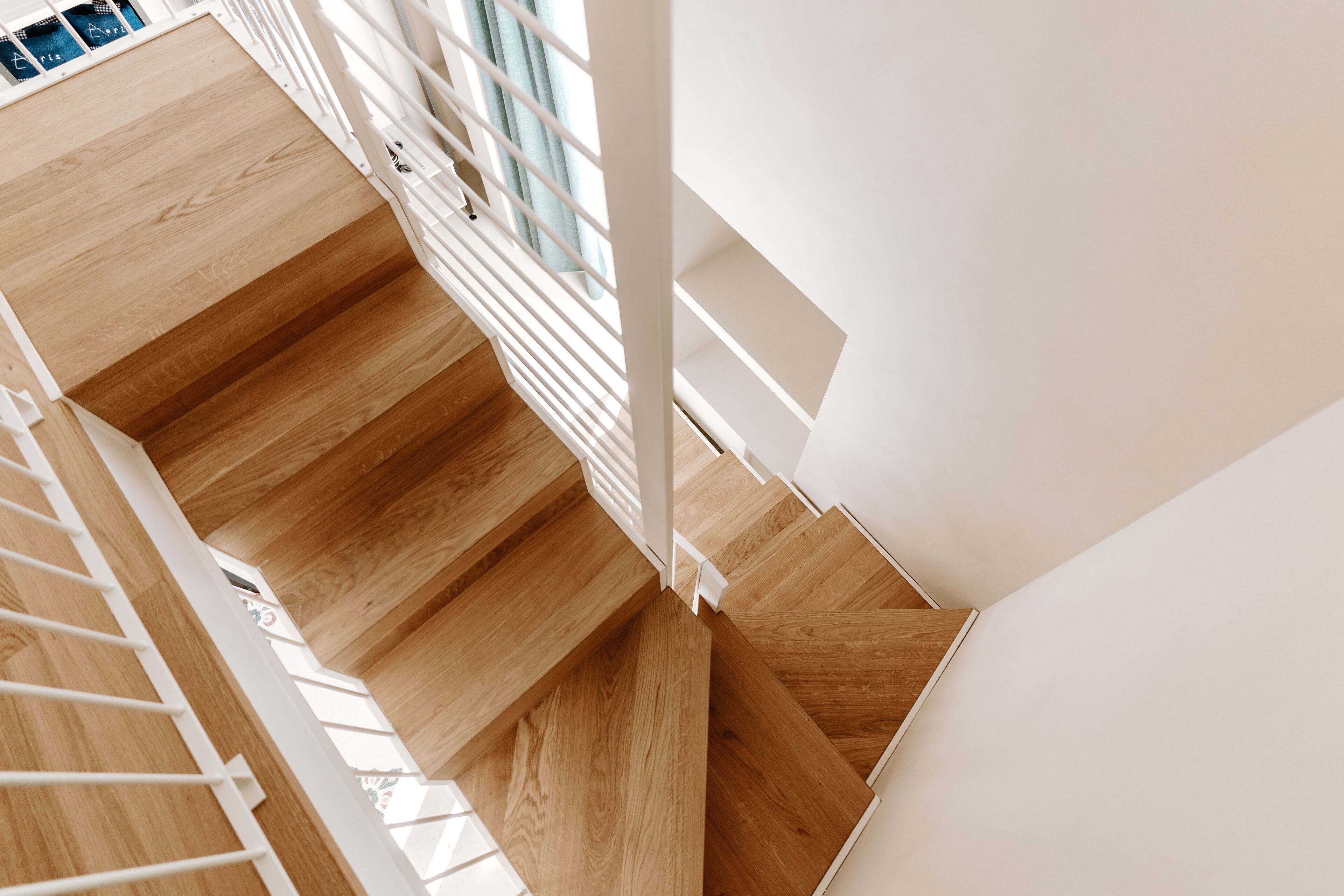 Una escalera de madera con barandillas blancas y vistas al piso superior.