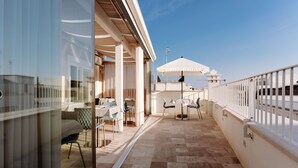 A balcony with outdoor seating, a table, and a large umbrella. - Aeris Suite & Relax (Polignano a Mare)