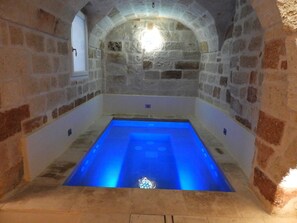 Ein Zimmer mit Steinwänden und einem rechteckigen Pool.