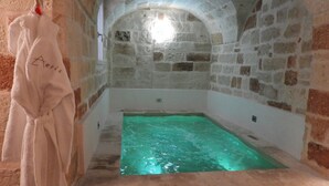A stone-walled room with a bathtub filled with water. - Aeris Suite & Relax (Polignano a Mare)