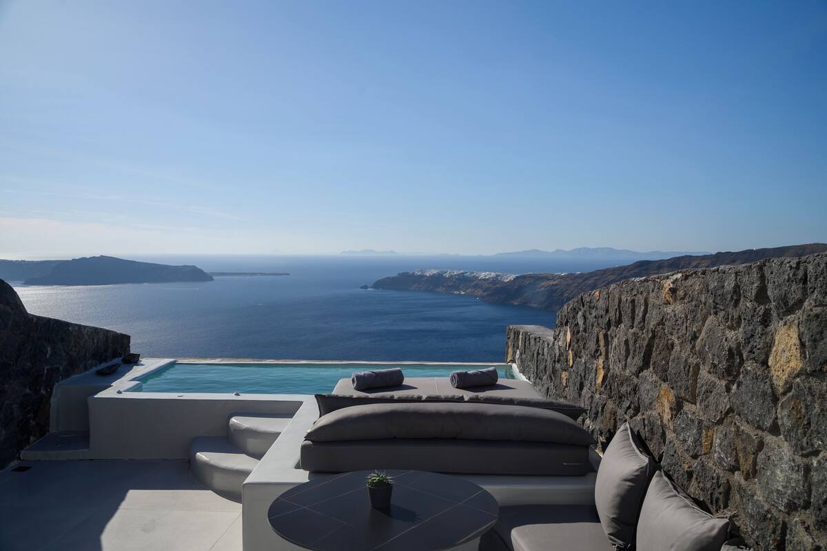 A modern outdoor seating area with a pool, overlooking a scenic coastline.