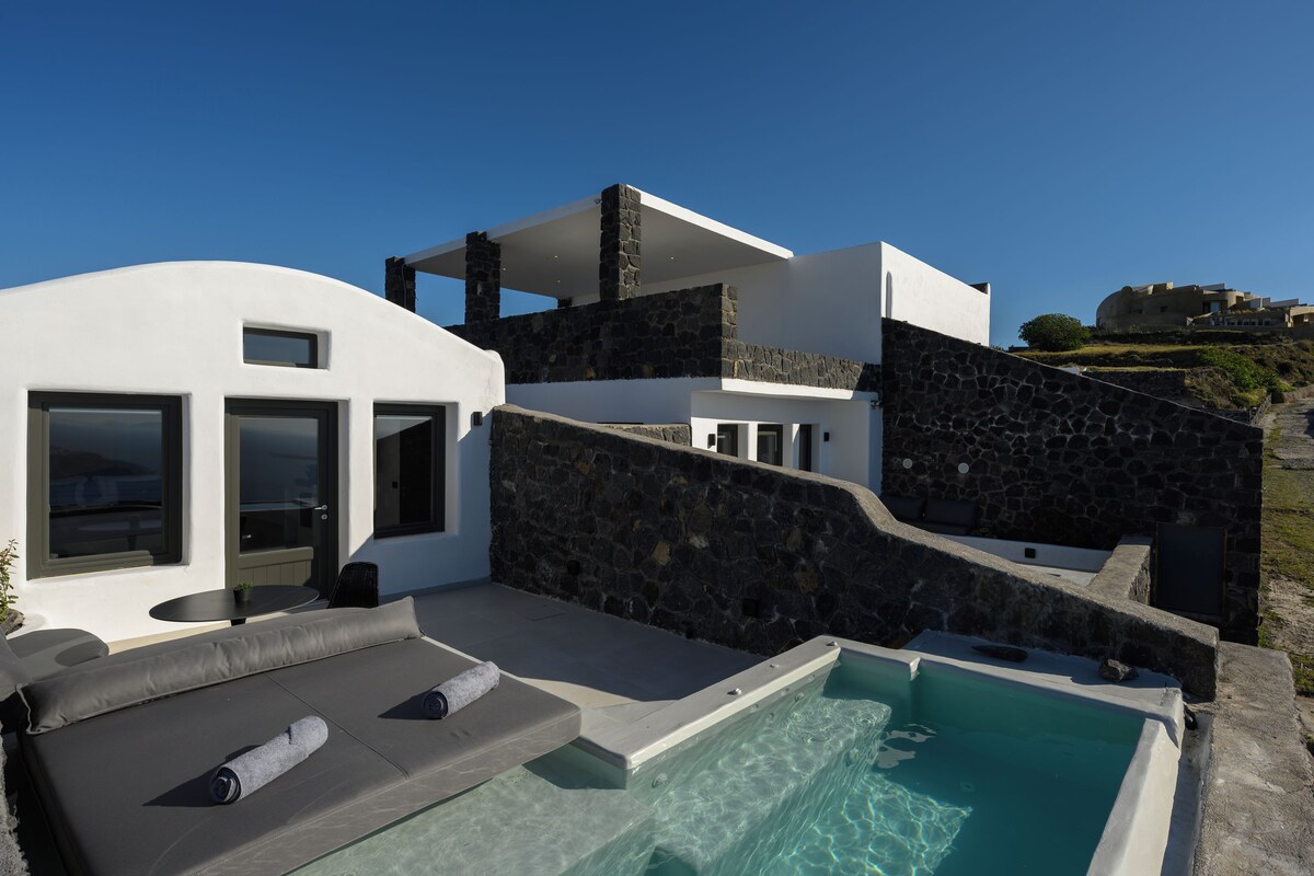 A modern villa with a pool, stone walls, and a view of a hill.