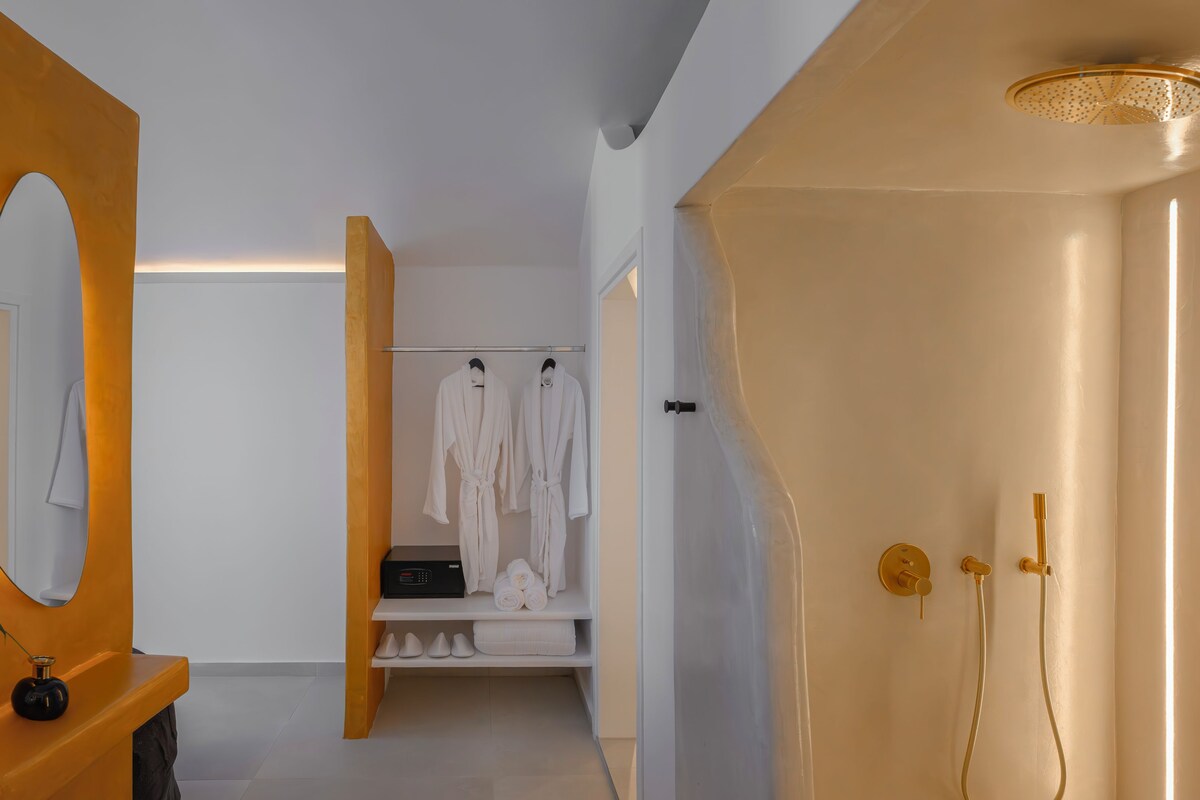 A modern bathroom with a walk-in shower, a vanity with a mirror, and a robe rack.