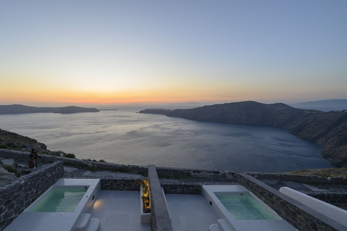 A spa area with two hot tubs overlooking a body of water and distant mountains.