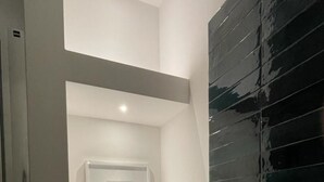 Casa de banho com parede revestida a branco, parede de destaque revestida a preto e um quadro na parede.