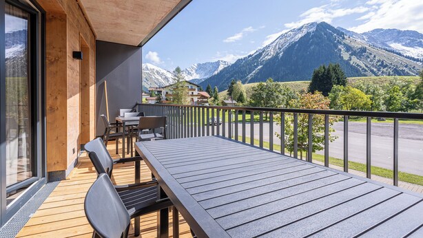 Ein Balkon mit Holzboden, Sitzgelegenheit und Blick auf die Berge.