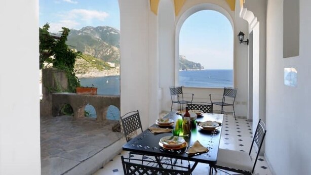 Comedor con una mesa dispuesta para cuatro, con vistas a la costa.