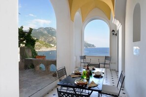A dining area with a table set for four, overlooking a coastal view. - Villa Sophia with private access to the sea (Minori)