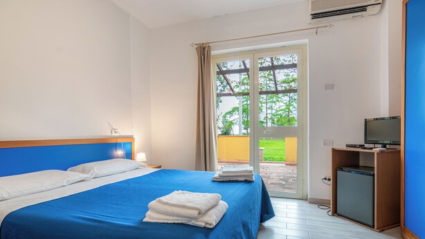 A hotel room with a large bed, a TV, and a small fridge. - Villaggio La Feluca (Isca sullo Ionio)